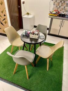 Comfortable 1 & 2 Bedroom Apartment in DHA by Virani في كراتشي: ثلاثة كراسي وطاولة على سجادة خضراء
