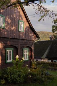 una casa in legno con finestre verdi e una recinzione di Chalupa na Valech a Krompach