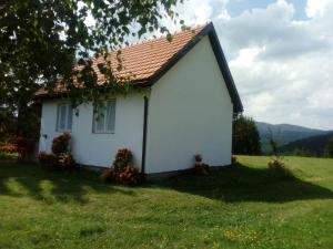 a small white house in a grassy field at Zlatarski Pogled in Nova Varoš