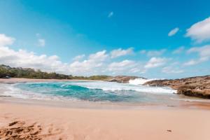 una playa de arena con olas en el océano en MAS102 Manati Amaizing Studio, en Manatí