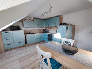 a kitchen with blue cabinets and a table and chairs at Ferienwohnung zur Eiche in Weißenfels