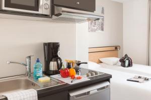a small kitchen with a sink and a microwave at Aparthotel Adagio Access Dijon République in Dijon