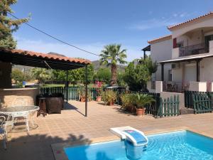 a patio with a pool and a table and a house at ilyda Residence apts in Skala Kallonis
