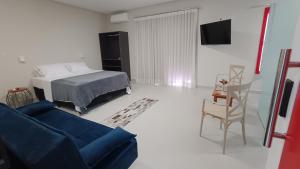 a living room with a bed and a blue couch at Suítes Nossa Senhora de Fátima in Pirenópolis