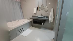 a white bathroom with a sink and a mirror at Suítes Nossa Senhora de Fátima in Pirenópolis +20 photos