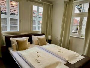 a bedroom with a large bed with two windows at Altstadt-Hotel Gosequell in Goslar