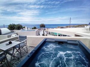 a hot tub on top of a building with a table at En Plo Boutique Suites in Oia