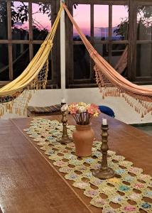 a table with a hammock and a vase of flowers on it at Poente Guest House in Conceição da Ibitipoca