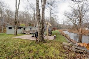a house with a picnic table next to a river at EV Serene Modern Cozy Waterfront Fireplace Cottage in Livingston Manor