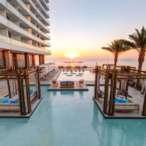 an image of a resort pool with chairs and the ocean at Stunning Beachfront 3-Bedroom Corner Residence in Hollywood