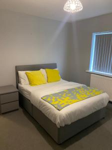 a bedroom with a bed with yellow pillows and a window at 15 on Hill Crescent, 6 en-suite bedrooms, Sleeps 12 in Skegby