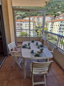 - Balcón con mesa blanca y sillas en Apartment 6 minutes from Monaco train station, en Beausoleil