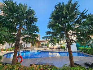 two palm trees in front of a swimming pool at B&C Staycation by SMDC Cheer Residence in Lias
