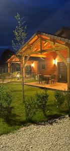 a pavilion with a table and benches in a yard at night at Les Chalets près de Chalain in Montigny-sur-lʼAin