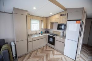 una cucina con frigorifero bianco e armadietti in legno di Grantown Getaway - SJA Stays - Modern 2 Bed Static a Grantown on Spey