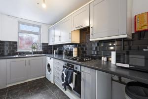 a kitchen with white cabinets and a stove top oven at Luxury 4-Bed Home Coventry - City Centre with FREE Parking & Garden in Coventry