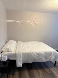 a bedroom with a white bed with a branch on the wall at 4 Bedroom House steps to 401, Perfect for long stays in Belleville