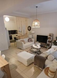 a living room with two white couches and a tv at Christi & Paris Nest in Volos