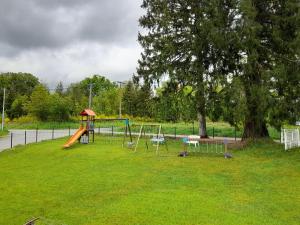 a park with a playground with slides and a tree at Au doux refuge in Saint-Exupéry-les-Roches
