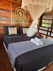 two beds in a room with wooden walls at Igapeba Hospedaria em Moreré in Cairu
