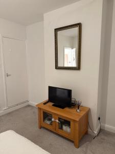 a room with a television on a table with a mirror at 2 Bedroom House in Nottingham +16 photos