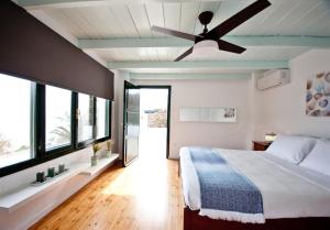 - une chambre avec un lit et un ventilateur de plafond dans l'établissement Villa Melydia, à Koundouros