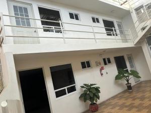 a white house with a balcony and a potted plant at SOFIA Hotel in San Miguel Tlamahuco