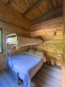 a bed in a log cabin with a bunk bed at RUKAKUTRAL refugio de bosque in Pucón