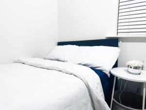 a bedroom with a bed with white sheets and a table at Luxury Room 8min to Sheffield City Center, Free parking in Manor