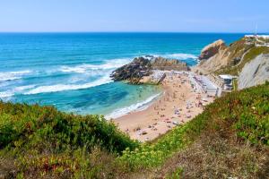 a beach with people on the sand and the ocean at Refúgio na Praia de Santa Cruz- A poucos passos da praia, surf e restaurantes in Santa Cruz