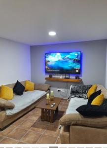 a living room with two couches and a flat screen tv at La Escondida in Burgohondo