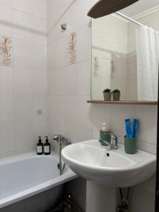 een witte badkamer met een wastafel en een bad bij 2х комнатная квартира в Центре города in Semey