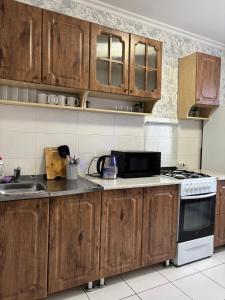 een keuken met houten kasten en een kookplaat met oven bij 2х комнатная квартира в Центре города in Semey +13 foto's