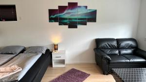 een woonkamer met een zwarte leren bank en een tafel bij Ingi's Guesthouse with a Car in Miðvágur