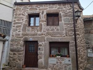 a stone house with a door and two windows at La Escondida in Burgohondo