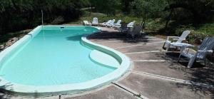 una piscina con un mucchio di sedie intorno di Cabañas Siesta Serrana a Río Ceballos