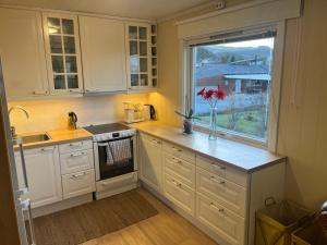 a kitchen with white cabinets and a vase of flowers on a counter at Cozy home with a fireplace, well connected to bus, quiet and view over the fjord in Trondheim