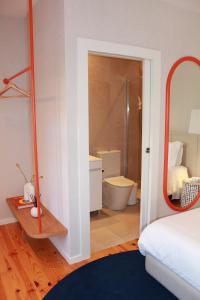 a bedroom with a bathroom with a mirror and a bed at O Laranjal in Guimarães +70 photos