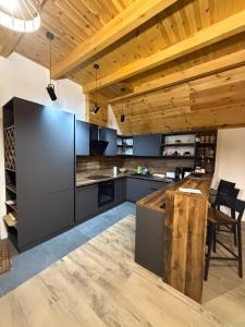 an open kitchen with wooden ceilings and a wooden table at A-Frame Belvedere Colibița in Colibiţa