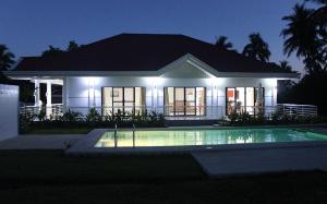 a house with a pool in front of it at night at Bohol White House Bed & Breakfast in Lila