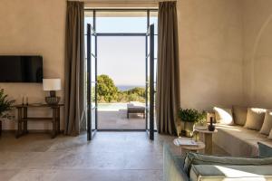 ein Wohnzimmer mit Sofa und Glasschiebetür in der Unterkunft Montesea - Luxury Nature Villas in Vasilikos
