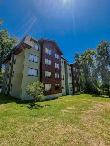 a large apartment building with a grassy yard in front of it at Departamento en Pucón - Camino al Volcan in Pucón