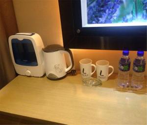 a counter with a microwave and two cups and water bottles at Lavande Hotel Lanzhou in Lanzhou
