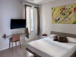 San Martino Suite - Pavia City - by HOST4U في بافيا: غرفة نوم بها سرير ومكتب وتلفزيون