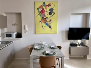 San Martino Suite - Pavia City - by HOST4U في بافيا: مطبخ مع طاولة مع كراسي و لوحة على الحائط +صورة واحدة