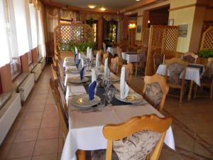 uma mesa longa num restaurante com mesas e cadeiras brancas em Motel Majolka em Ptuj