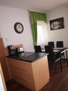 a kitchen with a table and a clock on the wall at Aquarosa Apartman in Hévíz