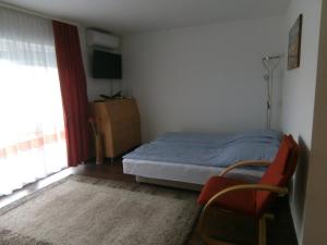 a bedroom with a bed and a chair and a window at Aquarosa Apartman in Hévíz