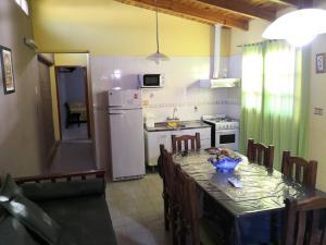 a kitchen with a table with chairs and a refrigerator at Apart Hotel Hualta Picum in San José de Jáchal