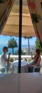 two people sitting at a table under an umbrella at Olguita in Menton